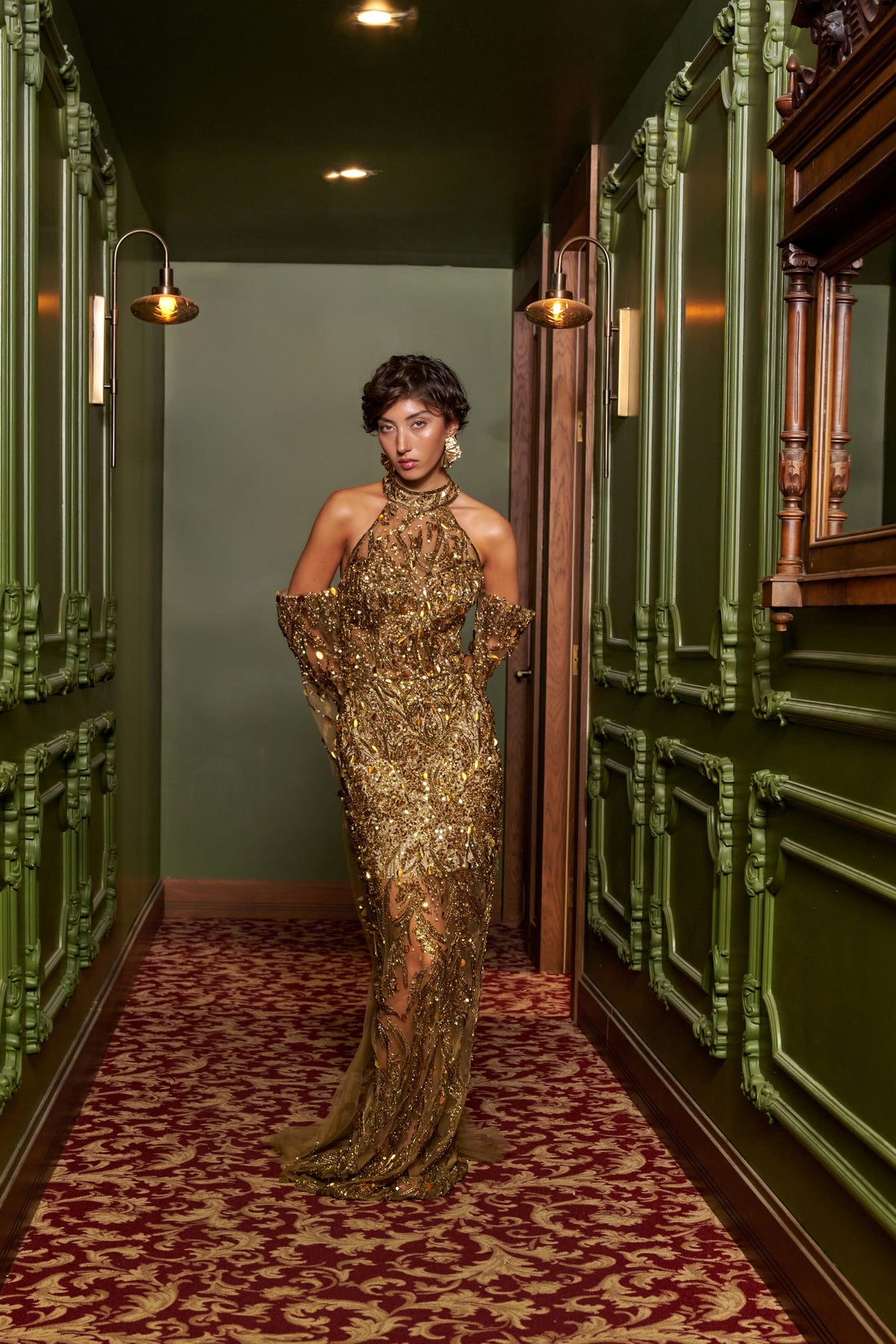 Golden Aura gold embellished evening gown with a halter neckline, open back, matching arm drape and floor-length train.