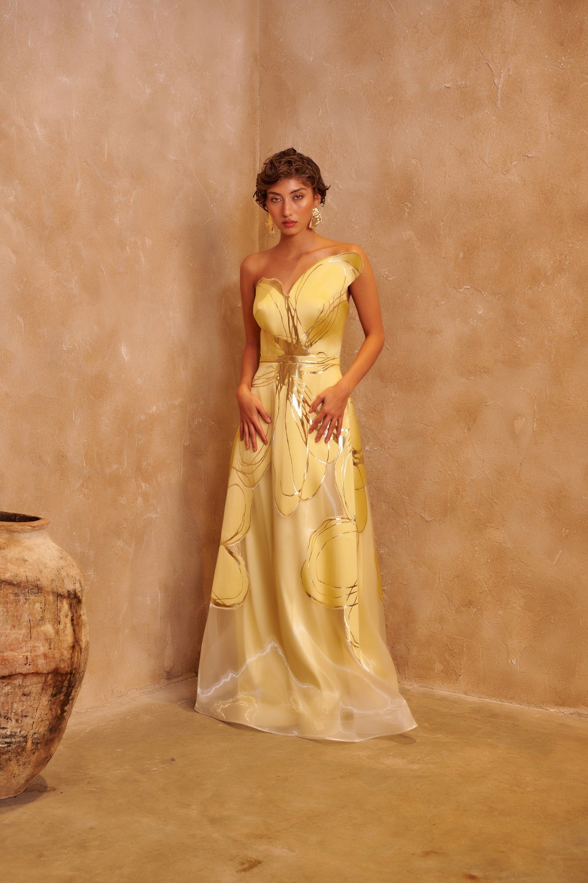 Golden Orbit yellow gown with a sculpted one-shoulder neckline, metallic swirl details and a defined waist.