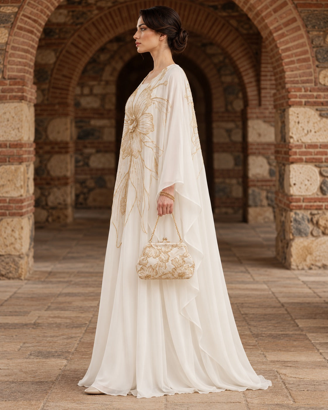 Zahra ivory kaftan abaya with an oversized gold floral motif, a rounded neckline and wide, draped sleeves, side view