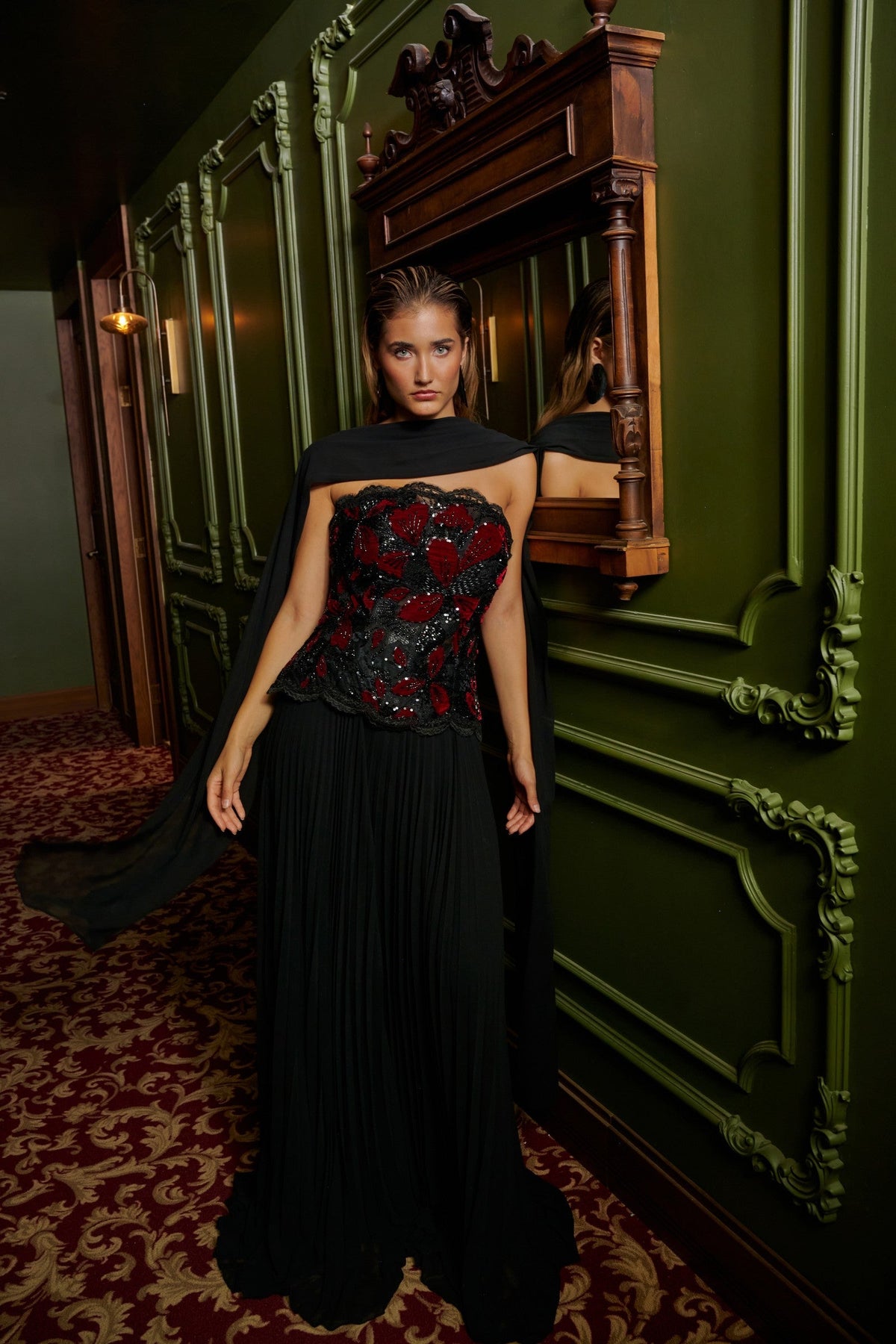 Floral Cascade evening gown in Black and Red with a strapless black and red floral-appliqué bodice, flowing pleated skirt and sheer draped scarf.