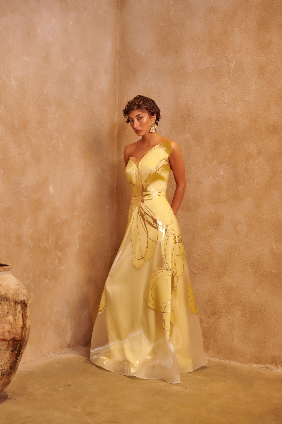Golden Orbit yellow gown with a sculpted one-shoulder neckline, metallic swirl details and a defined waist.