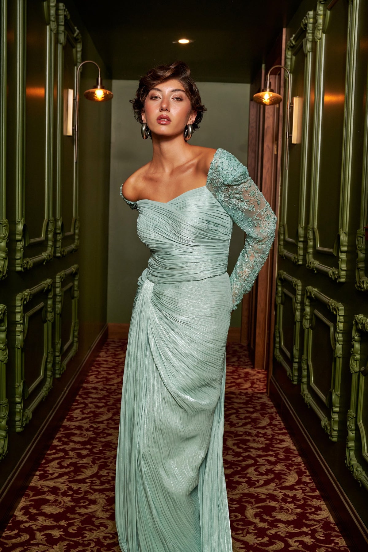 Mint Grace mint green draped evening dress with an asymmetric neckline, lace sleeve and floor-length silhouette.
