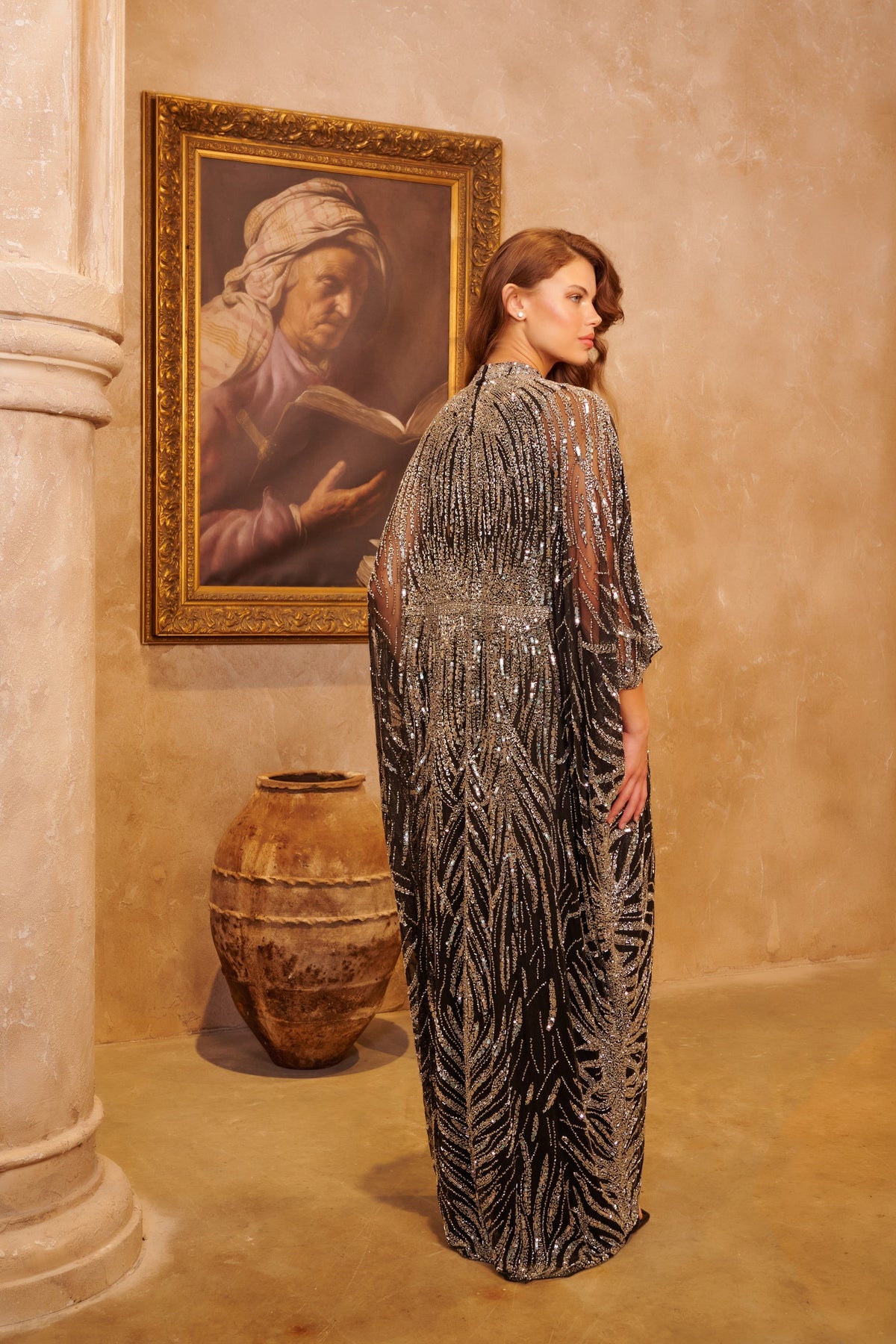 Silver Shahrazad black kaftan gown with ornate silver embellishment, a high neckline and flowing cape sleeves.