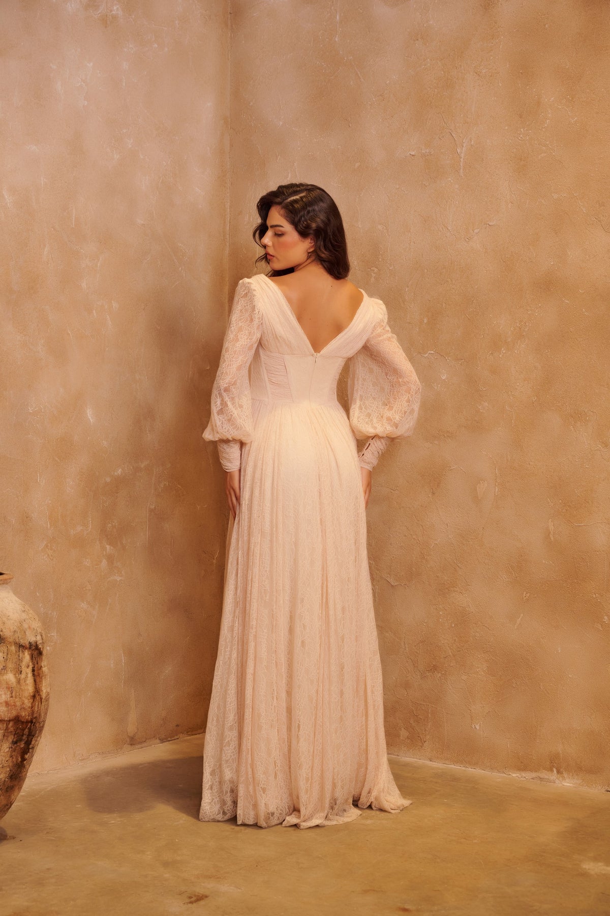 Ivory Waltz pleated gown with long sleeves, a corset waist and a flowing floor-length skirt.