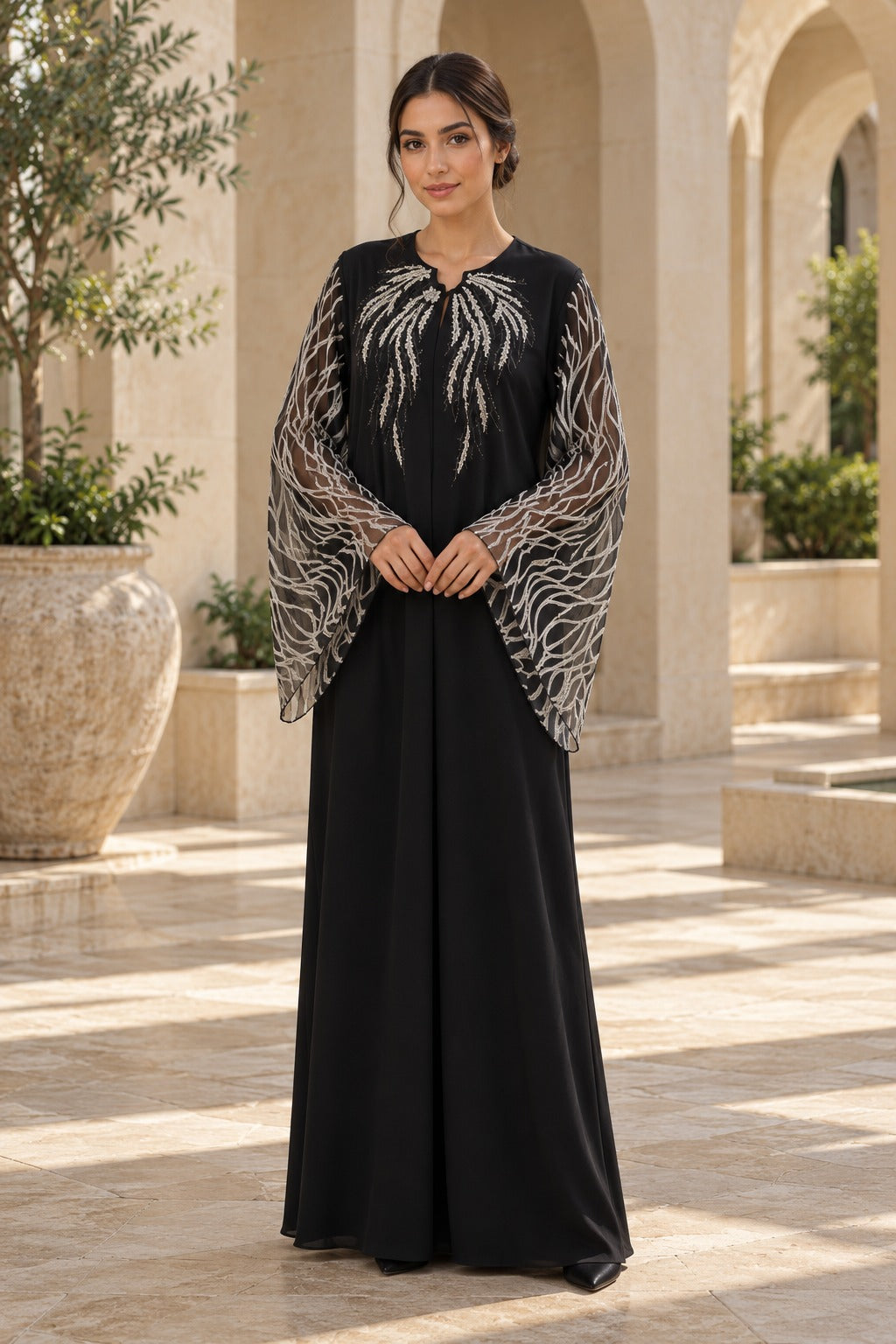 Serein black evening abaya with silver-toned neckline embellishment and sheer flared sleeves featuring leaf-like patterns, front view