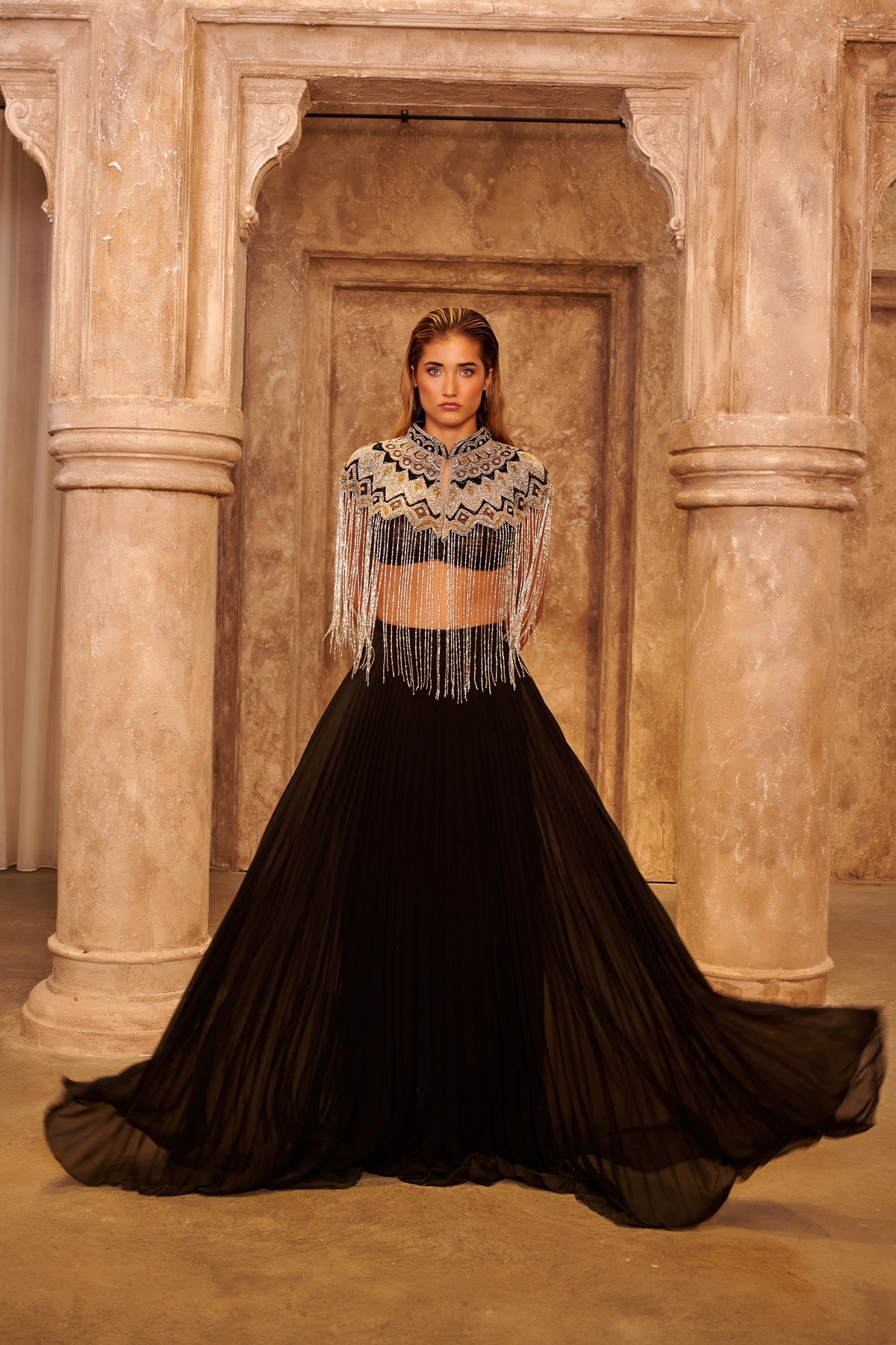 Silver Wings black evening gown with a geometric embellished cropped cape, cascading fringe and a voluminous floor-length skirt.