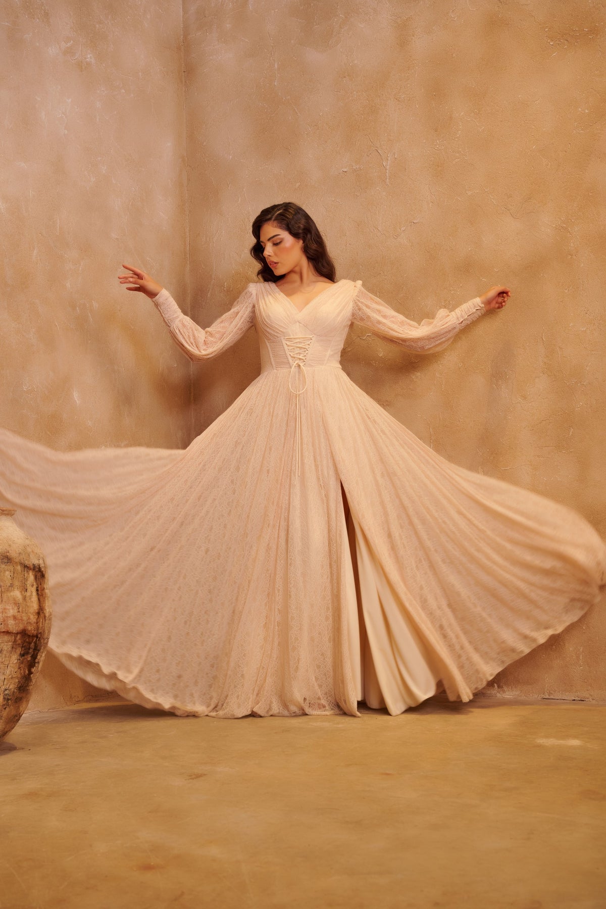 Ivory Waltz pleated gown with long sleeves, a corset waist and a flowing floor-length skirt.