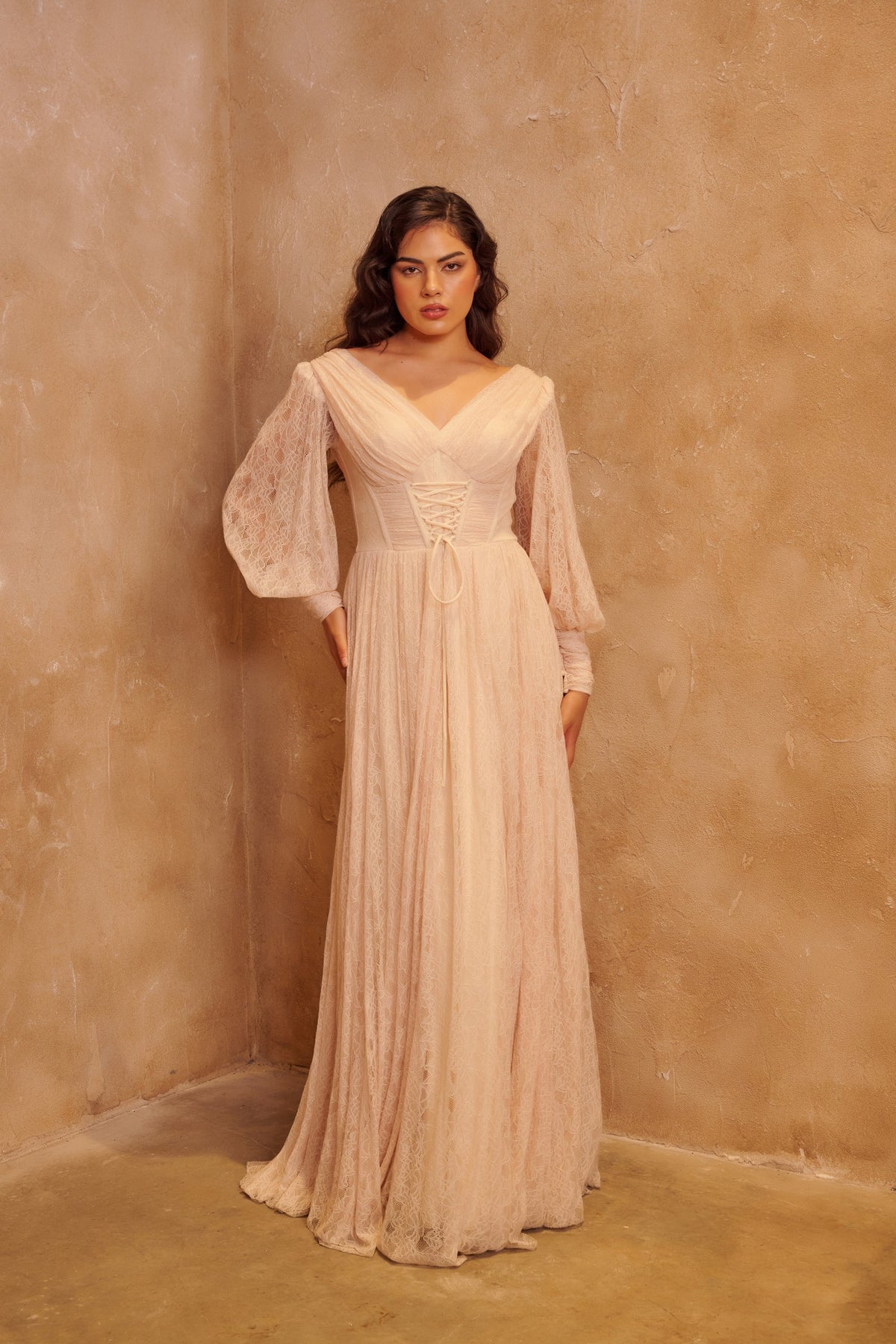 Ivory Waltz pleated gown with long sleeves, a corset waist and a flowing floor-length skirt.
