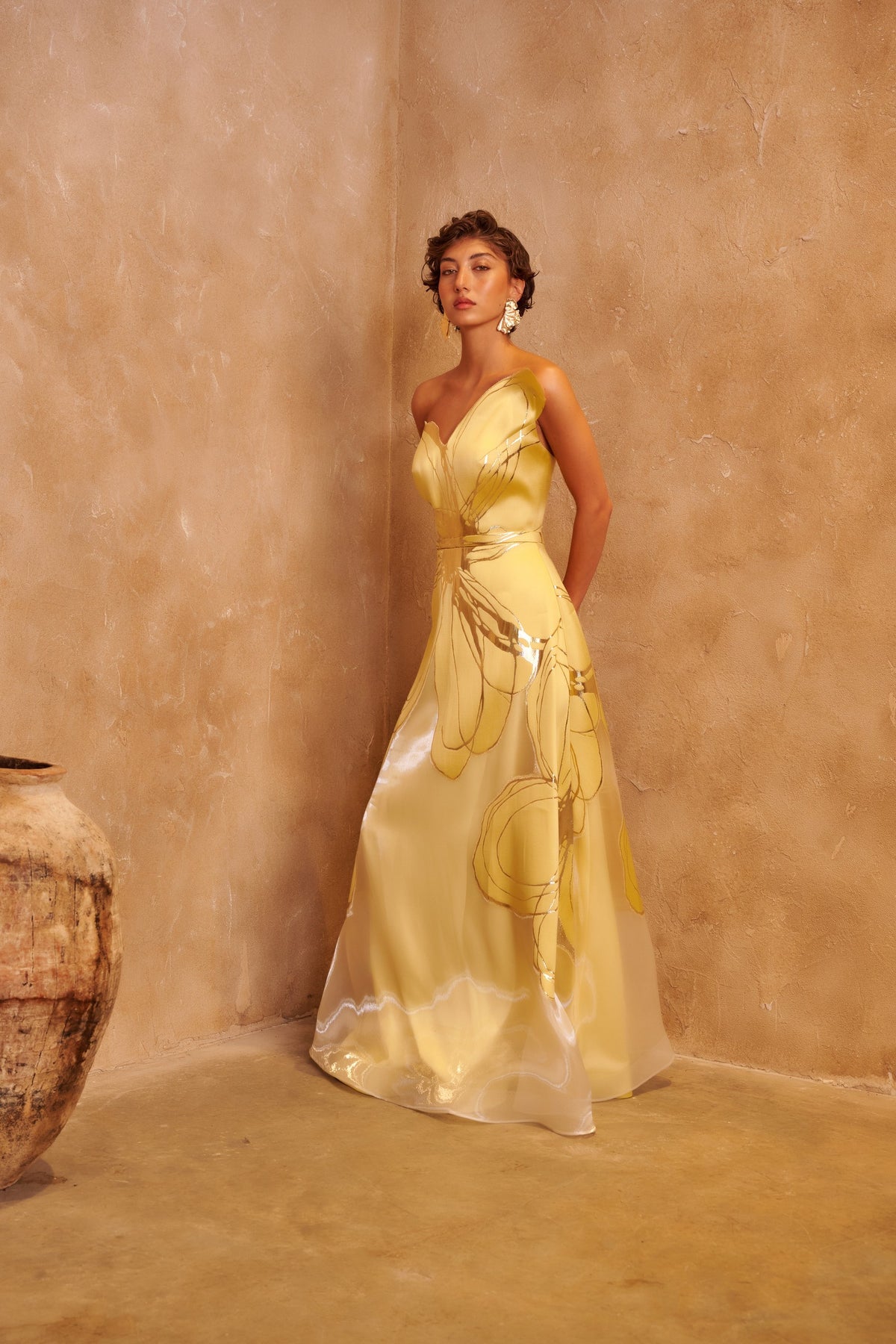 Golden Orbit yellow gown with a sculpted one-shoulder neckline, metallic swirl details and a defined waist.