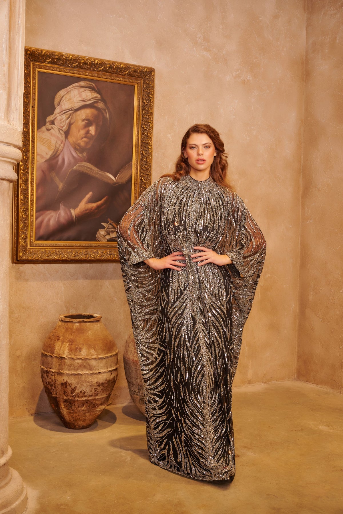 Silver Shahrazad black kaftan gown with ornate silver embellishment, a high neckline and flowing cape sleeves.