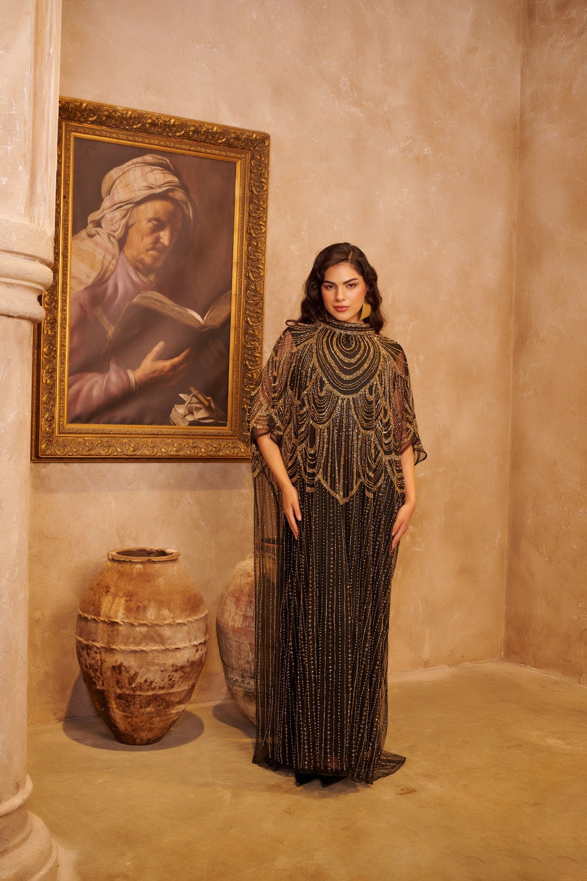 Golden Shahrazad black kaftan gown with ornate gold embellishment, a high neckline and dramatic cape sleeves.