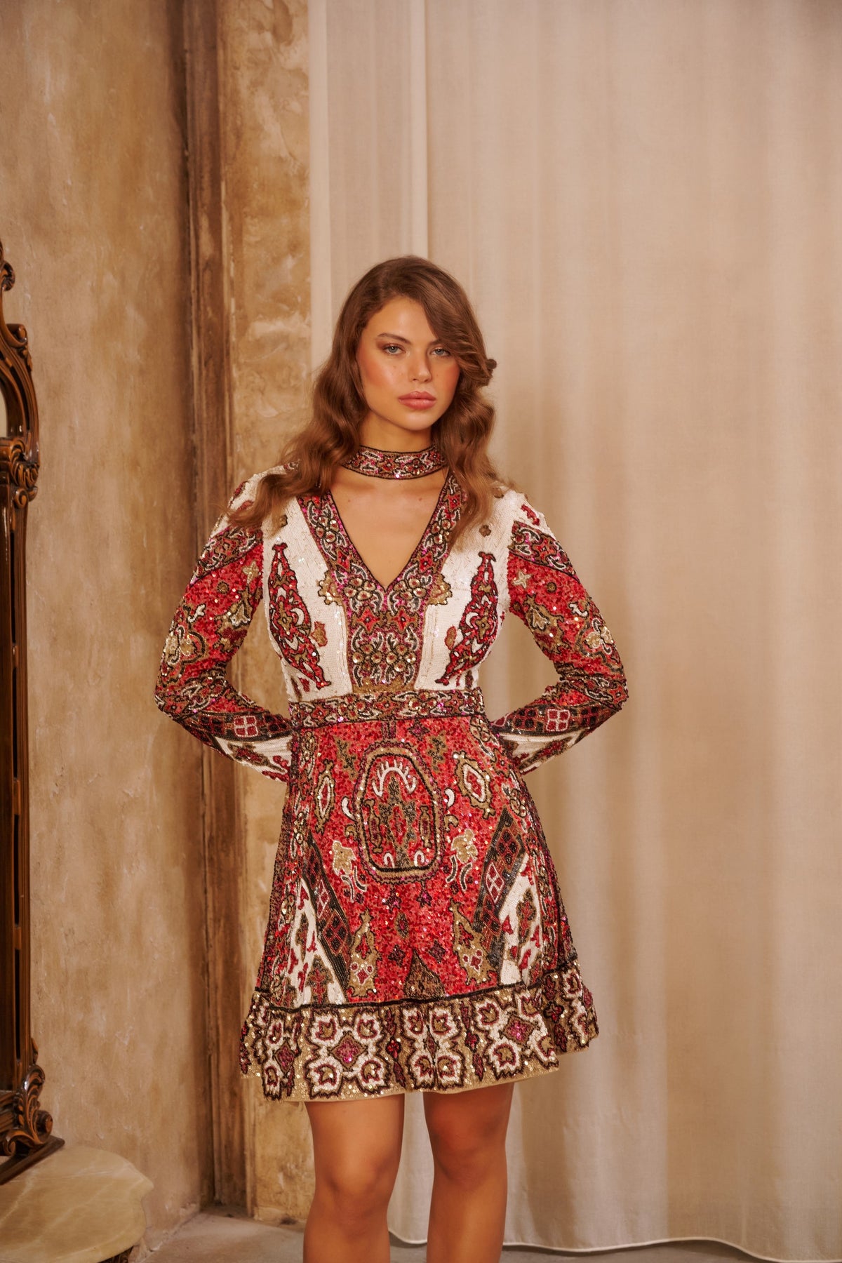 Crimson Mosaic red printed mini dress with long sleeves, a deep V-neckline and ornate oriental-inspired pattern.