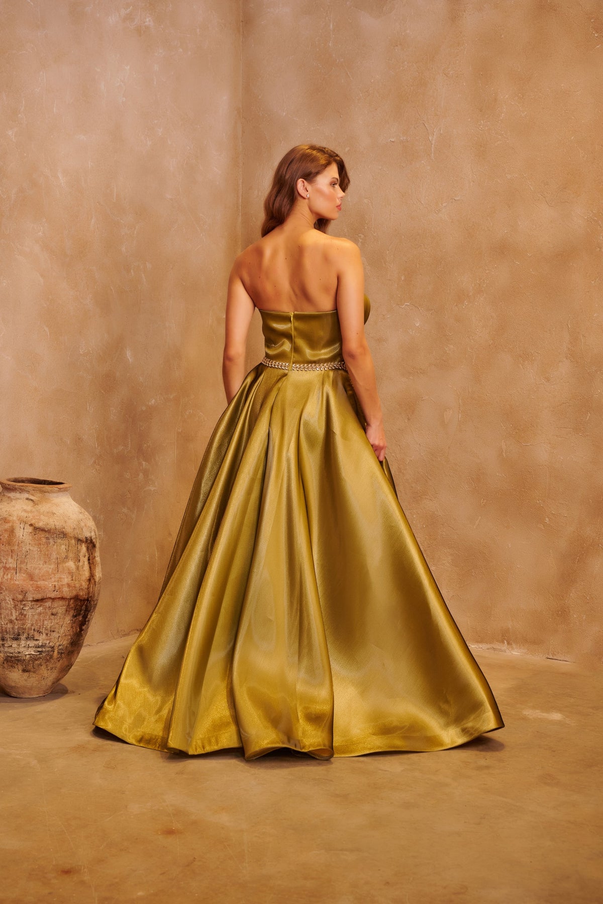 Gilded Olive satin gown with a sculpted strapless bodice, crystal waist detail and a full skirt.