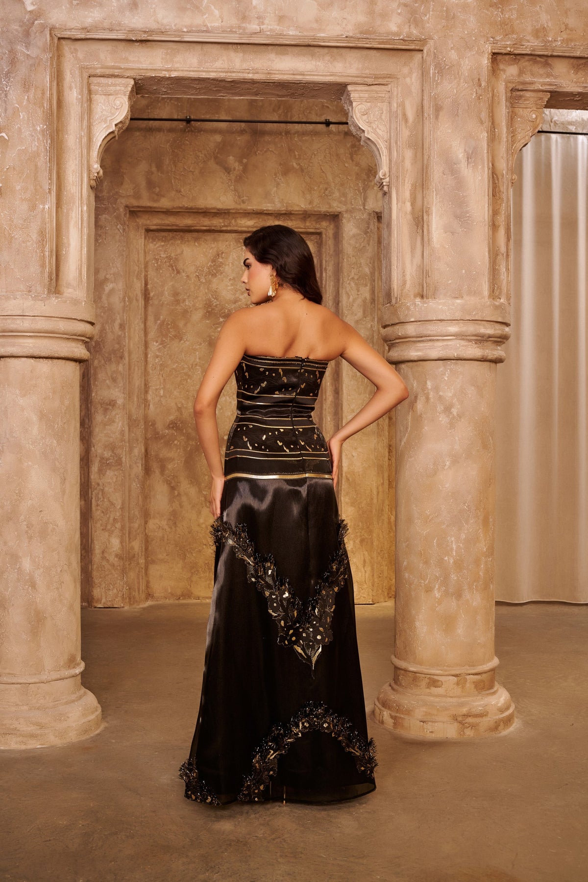 Golden Frame black evening gown with a strapless bodice, gold bands and an ornate embellished floor-length overlay.
