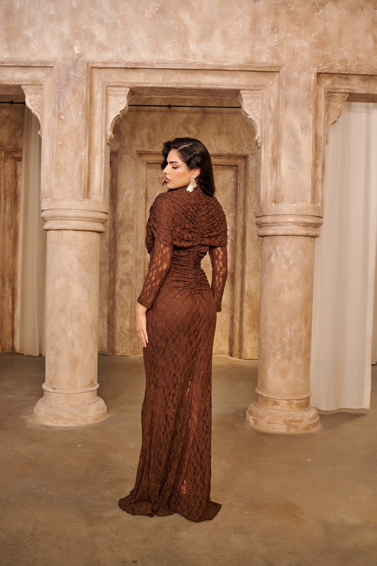 Cocoa Lace brown evening dress with long sheer sleeves, a draped bodice and a fitted floor-length mermaid silhouette.