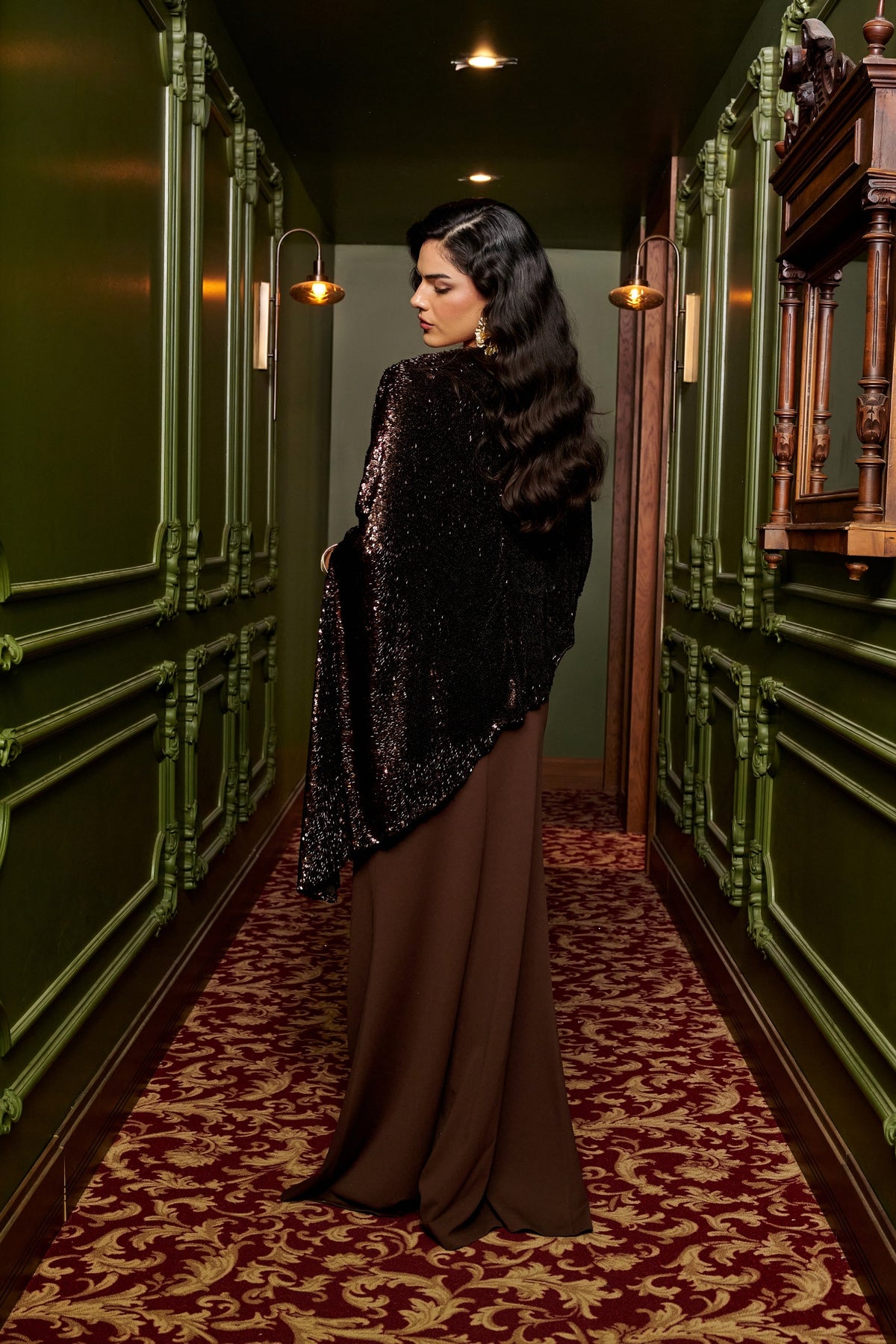 Mocha Glow chocolate brown evening gown with an asymmetric black sequin cape overlay and a floor-length fitted skirt.