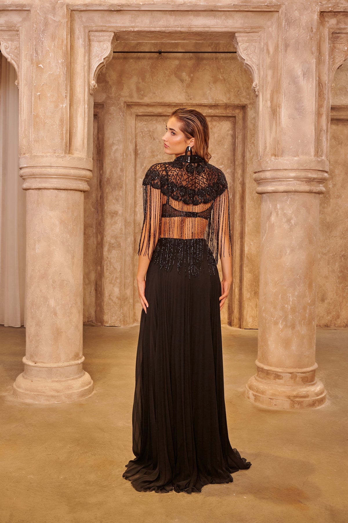 Midnight Fringe black evening gown with a beaded cape overlay, waist cutout, cascading fringe and a floor-length skirt.