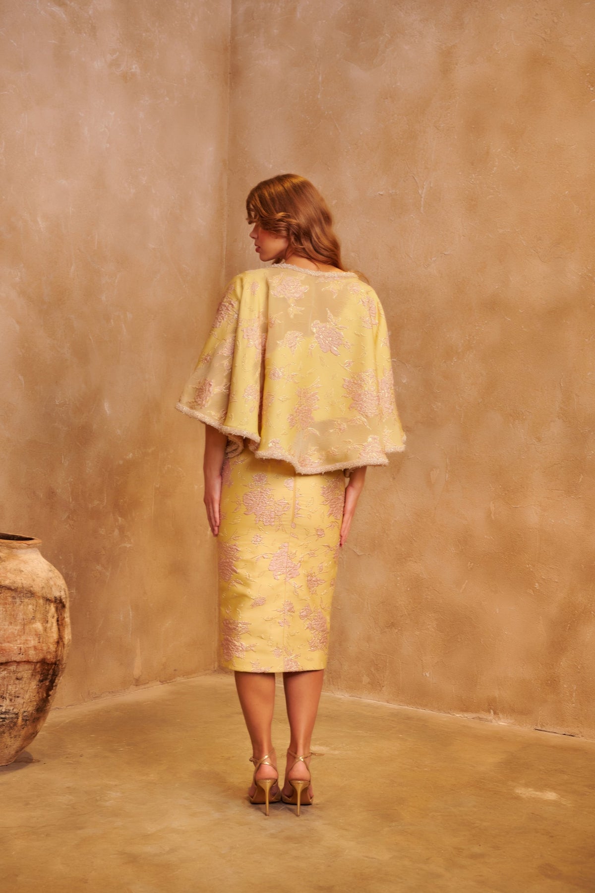 Golden Peony yellow brocade couture set with a cape jacket, fitted midi skirt and blush waist sash.